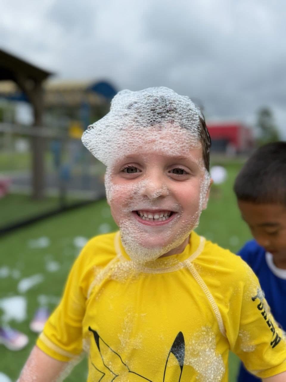 Child covered in bubbles during outdoor play day