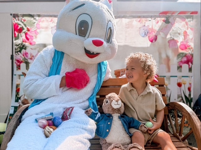 Child sitting with Easter bunny mascot at St. Peter's Academy