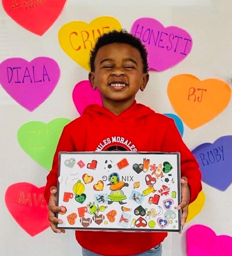 Child holding Valentine's Day gift in front of heart decorations